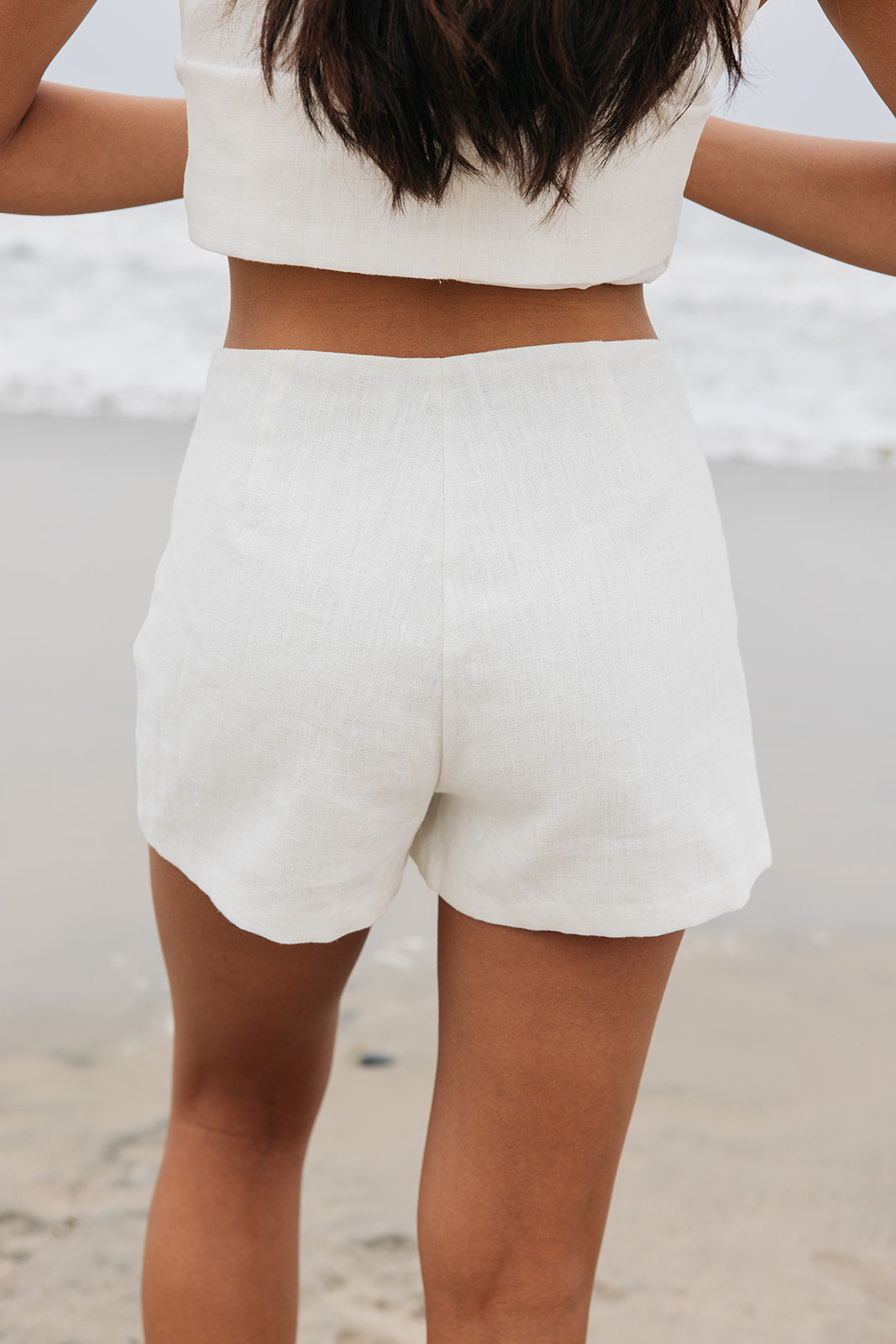 Woman wearing tailored white linen shorts on the beach
