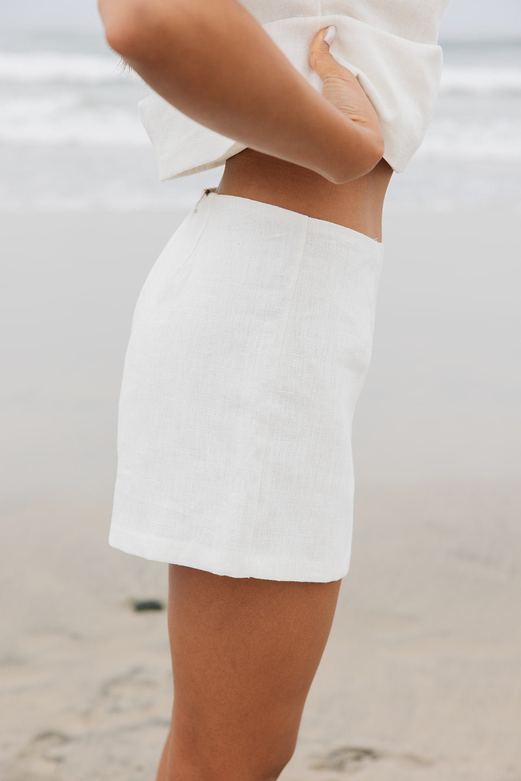 Woman wearing tailored white linen mini shorts on the beach