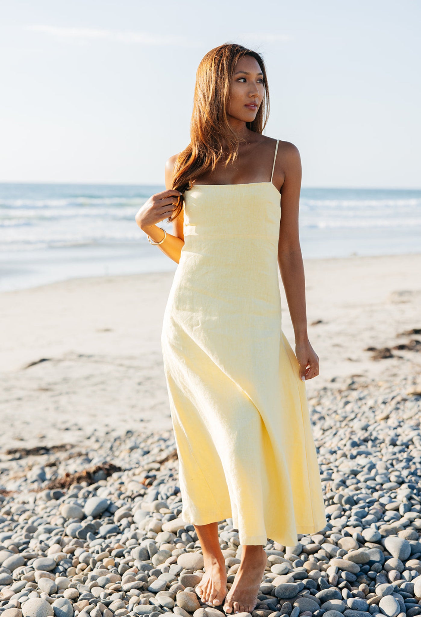 Model wearing Margot Linen Maxi Dress in yellow | linen | styled with gold jewelry | at the ocean