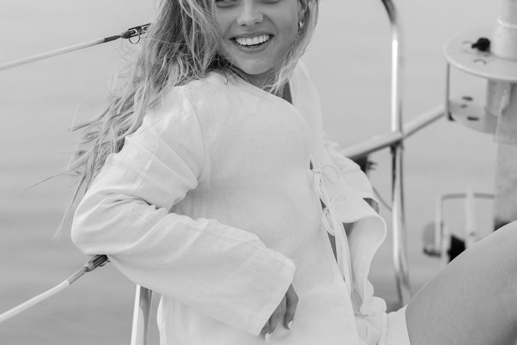 Black and white photo of a girl wearing a linen shorts and top set on a sailboat
